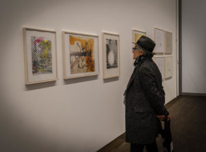 Mann betrachtet eine Bilderwand mit zeitgenössischer Kunst