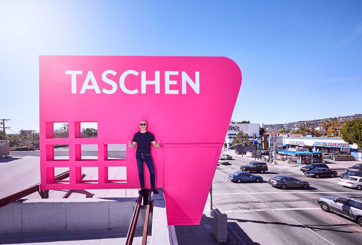 Benedikt Taschen oben auf dem rosa TASCHEN-Schild in L.A. © Foto: Mark Seelen