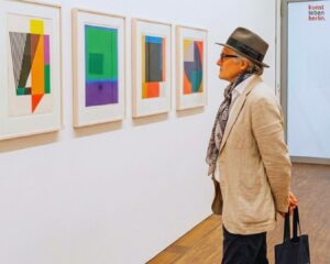 Mann betrachtet farbige Editionen, ein Blick auf zeitgenössische Kunst Preise in einer Berliner Galerie