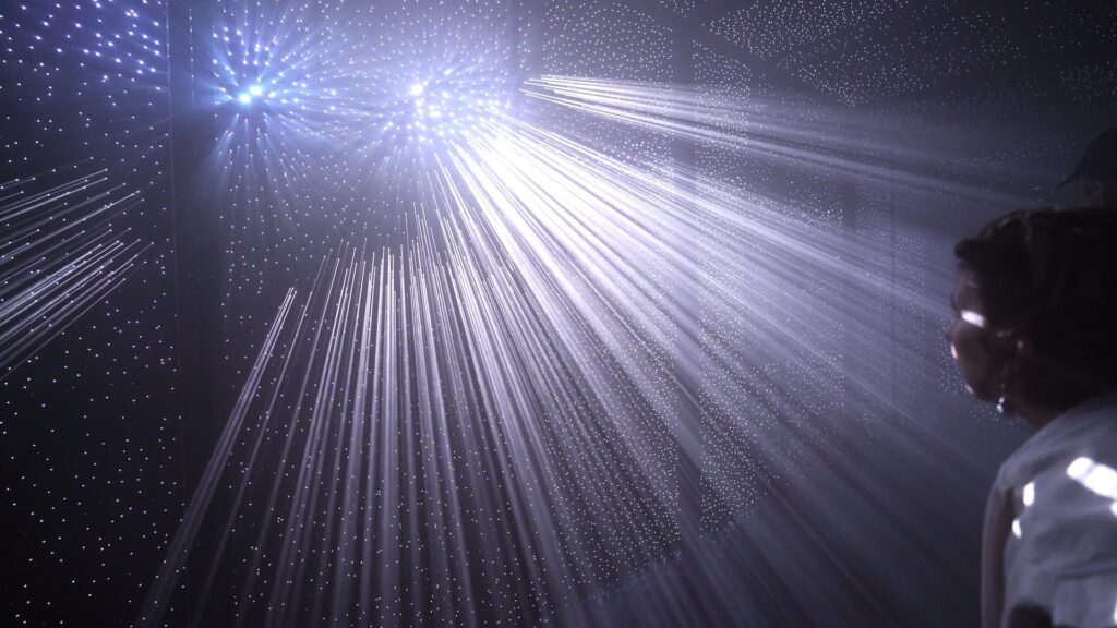 Himmel unter Berlin: Lichtstrahlen fallen durch Nebel auf eine Besucherin im dunklen Kellergewölbe