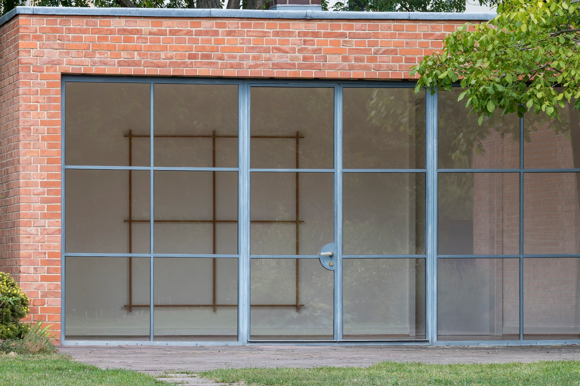 Installationsansicht Matt Browning A Screen of Trees im Mies van der Rohe Haus Berlin, Holzskulptur hinter der Glasfassade